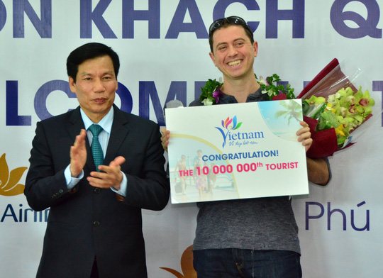 Bộ trưởng Bộ VHTTDL Nguyễn Ngọc Thiện tặng hoa chào mừng vị khách quốc tế thứ 10 triệu trong năm 2016. Ảnh: nld.com.vn